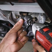 Person using a Milwaukee power tool on a vehicle's undercarriage.
