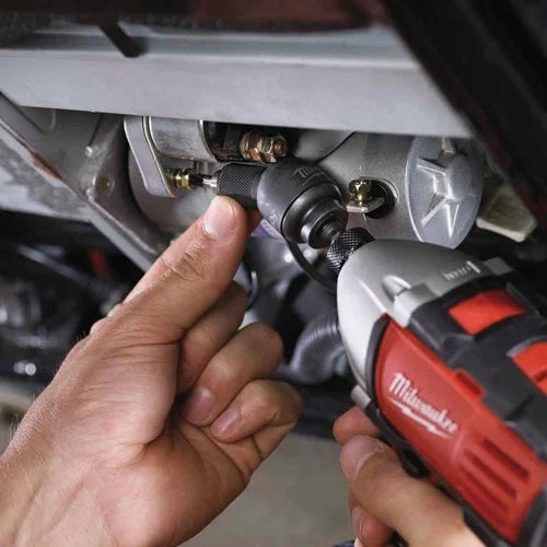Person using a Milwaukee power tool on a vehicle's undercarriage.