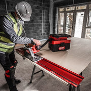 Person using a circular saw on a workbench with a Milwaukee toolbox in a construction setting.