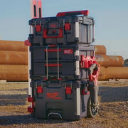 Stack of Milwaukee toolboxes in an outdoor setting with pipes in the background