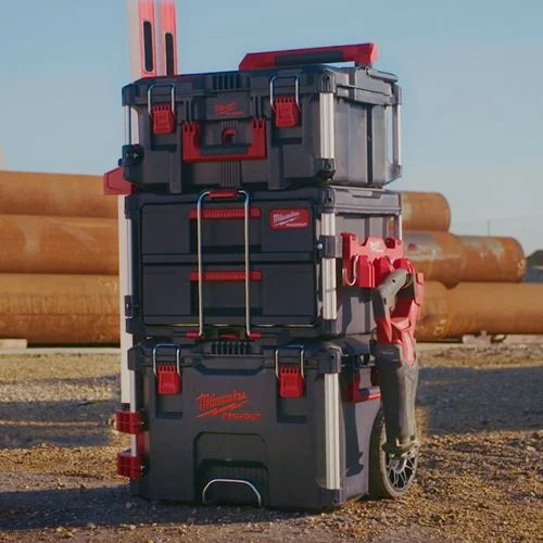 Stack of Milwaukee toolboxes in an outdoor setting with pipes in the background