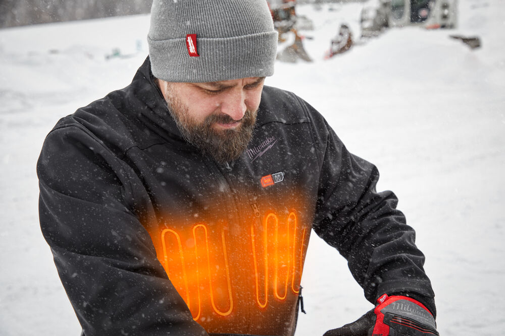 A worker wearing a heated Milwaukee jacket in black in a cold outdoor environment.