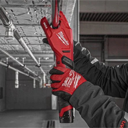 Person wearing red Milwaukee gloves holding a power tool in an industrial setting