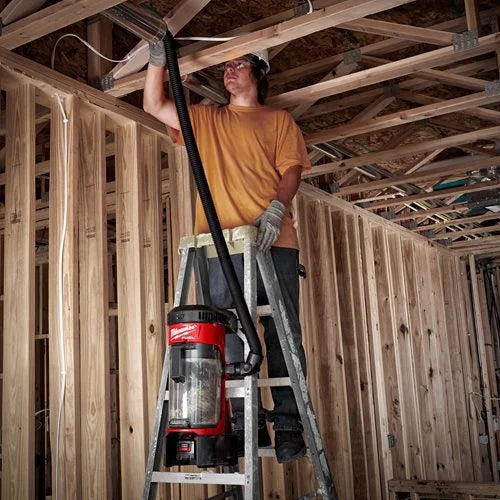 Person on a ladder using a vacuum cleaner in a wooden structure