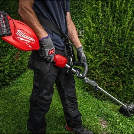 Person using a Milwaukee cordless grass trimmer on grass