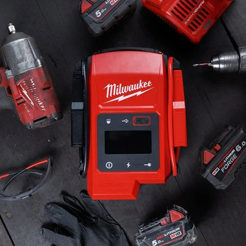 Milwaukee M18 Jump Starter JS2000-0 placed on workbench surrounded by M18 tools and accessories