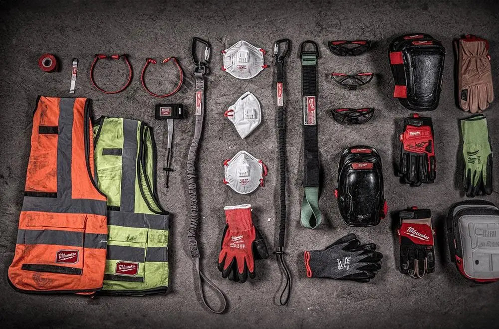 Collection of milwaukee ppe safety gear including vests, gloves, and protective equipment on a dark surface