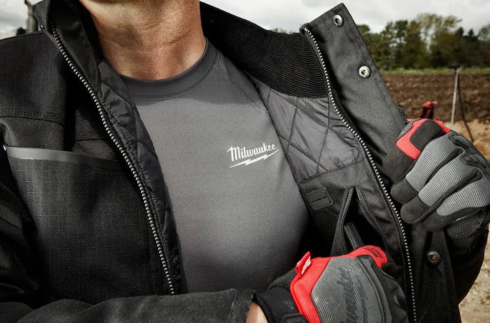 Person wearing a Milwaukee branded shirt and gloves in an outdoor setting